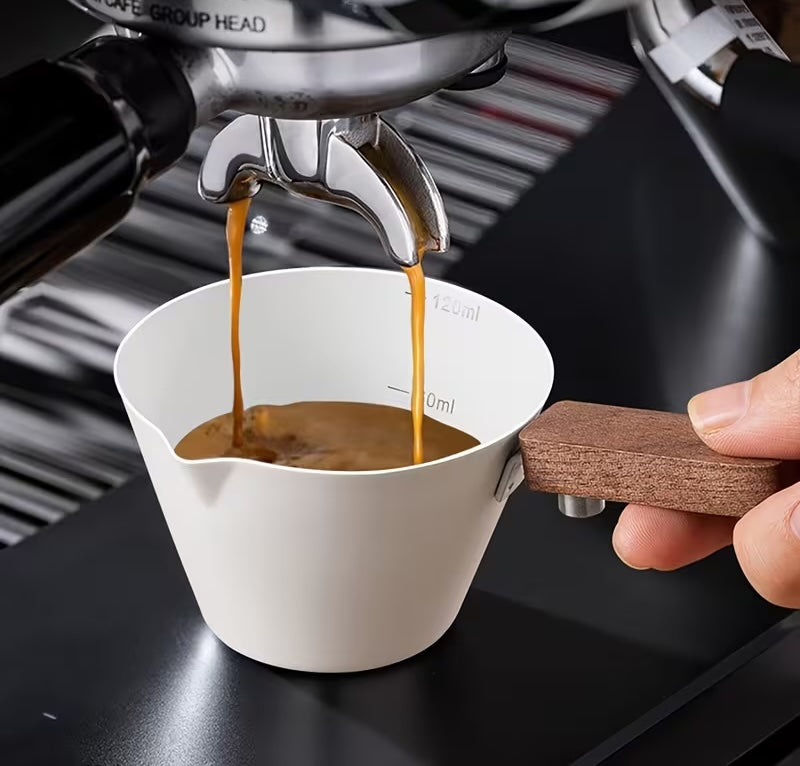 Metal measuring cup with wooden handle on a white background