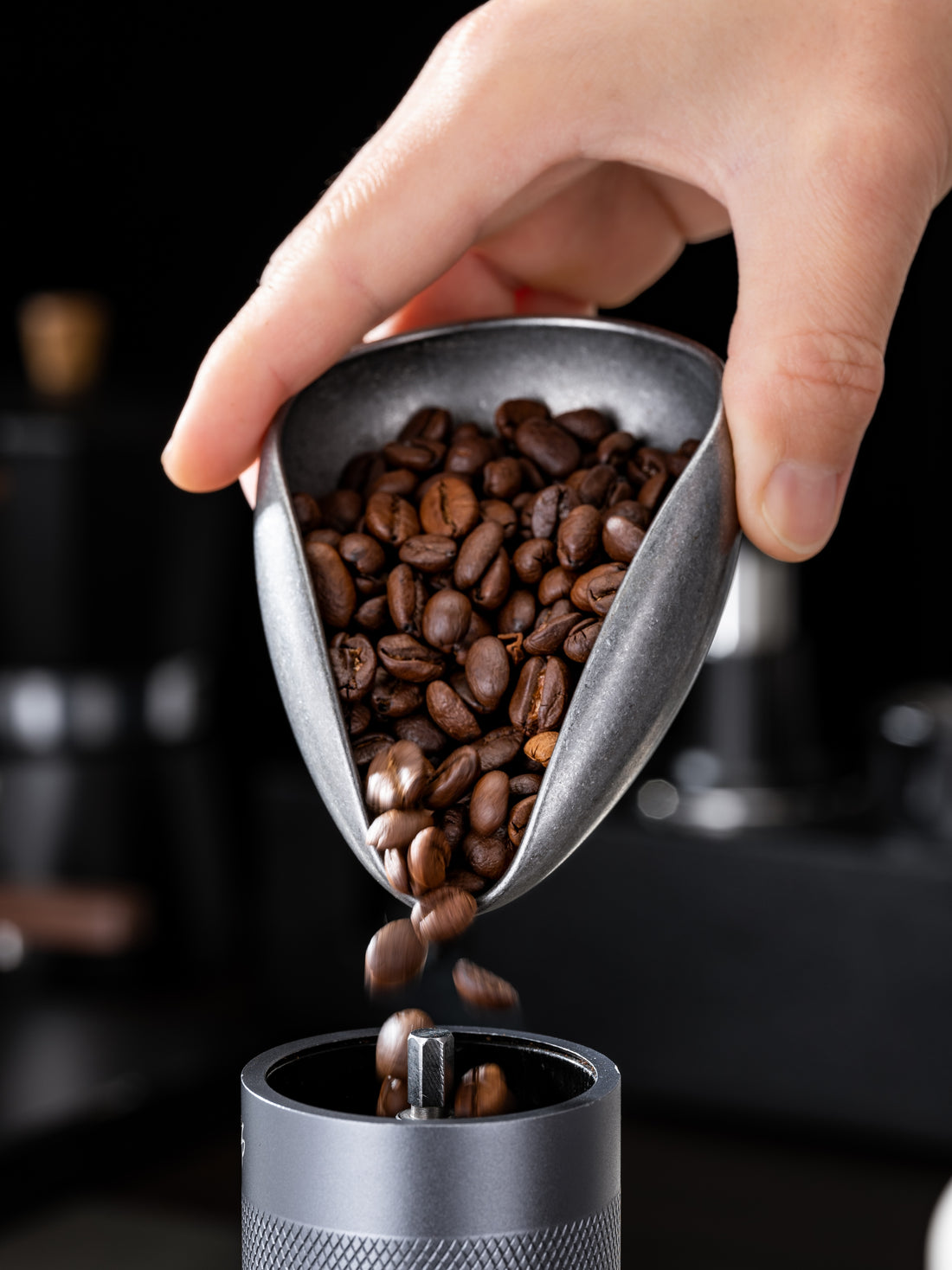 Triangular metal container filled with coffee beans on a gray surface